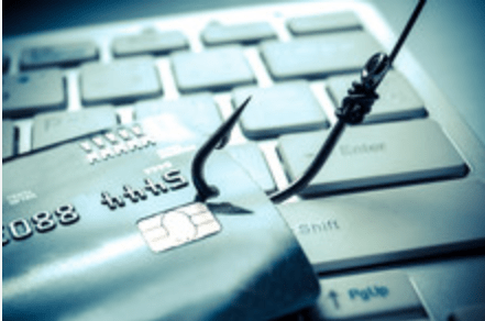 Credit card hooked on a phishing lure above a computer keyboard, representing scam alerts and analysis.